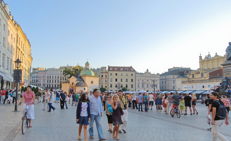 9 - A lively scene in the Main Market Square in Kraków, Poland, featuring the historic Church of St. Adalbert with its characteristic green dome in the background